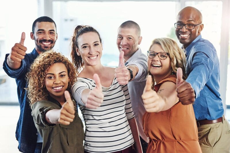 six people in an office doing a thumbs up